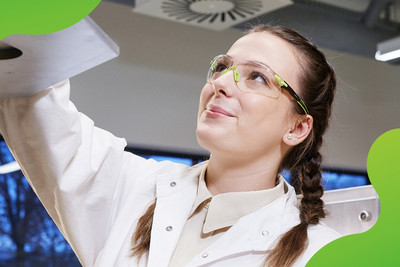 Eine junge Frau, die im Labor eine Maschine betätigt. 