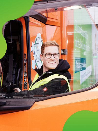 Mann steigt in einen orangen LKW ein und schaut lachend auf die Seite 