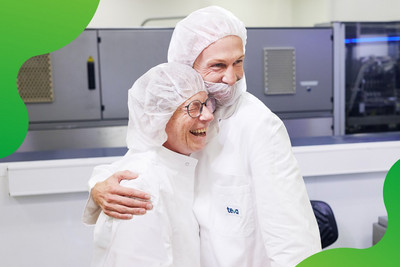 Zwei Mitarbeitende einer pharmazeutischen Produktion, die miteinander sprechen. 