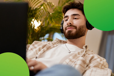 Junger Mensch, der in einer lockeren Atmosphäre an einem Computer arbeitet. 