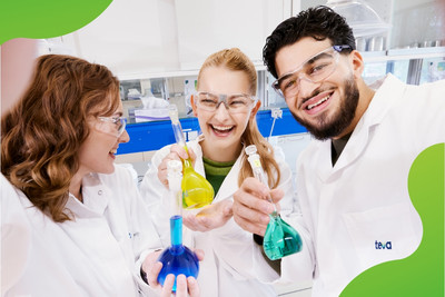 Drei junge Personen in einem Labor die lachen und Reagenzgläser in der Hand halten.