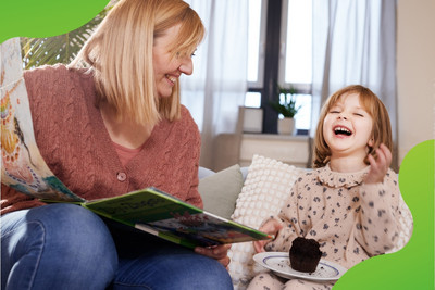 Eine Frau und ein Kind schauen sich ein Buch an. Beide lachen herzlich. Die Mutter schaut dabei ihr Kind an.