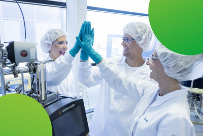 Drei Mitarbeitende im Labor stehen zueinander und geben sich lachend ein High Five. 