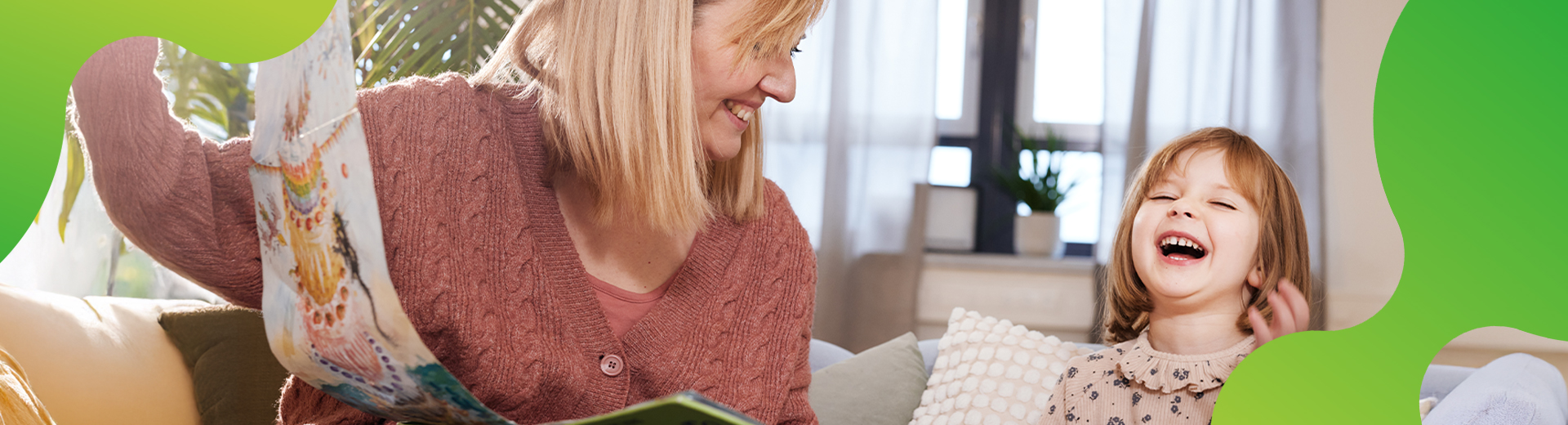 Eine Frau und ein Kind schauen sich ein Buch an. Beide lachen herzlich. Die Mutter schaut dabei ihr Kind an.