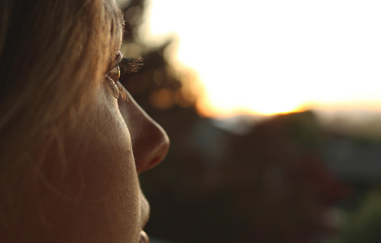 Eine Frau schaut in die Ferne und erinnert sich an die schlimmen Gefühle während ihrer ersten Migräneattacke