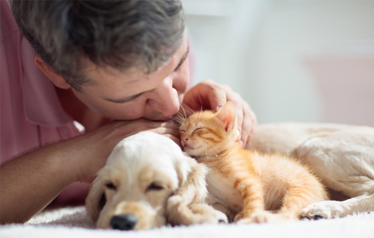 Ein Mann, der mit einem Kätzchen und Welpen kuschelt und die Vorteile von Haustieren für die mentale Gesundheit genießt