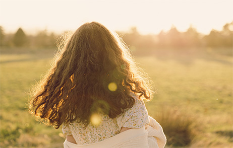 Junge Frau schaut in den Sonnenaufgang