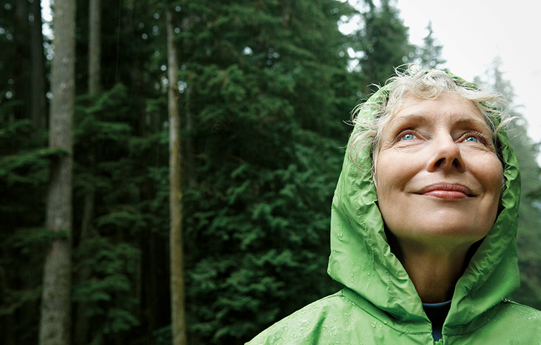 Frau im Wald, aufmerksamer glücklicher Blick zu den Bäumen.