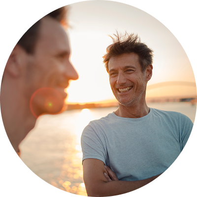 Zwei Männer lachen gemeinsam im Gegenlicht eines Sonnenuntergangs