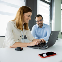 Frau und Mann sitzen am Laptop