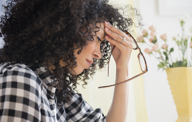 Frau mit Brille hält sich den Kopf