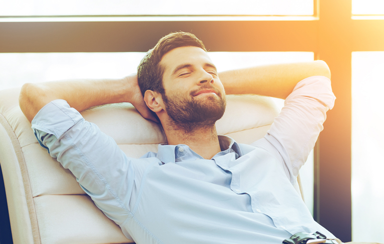 Zufriedener Mann mit hinter dem Kopf verschränken Händen.