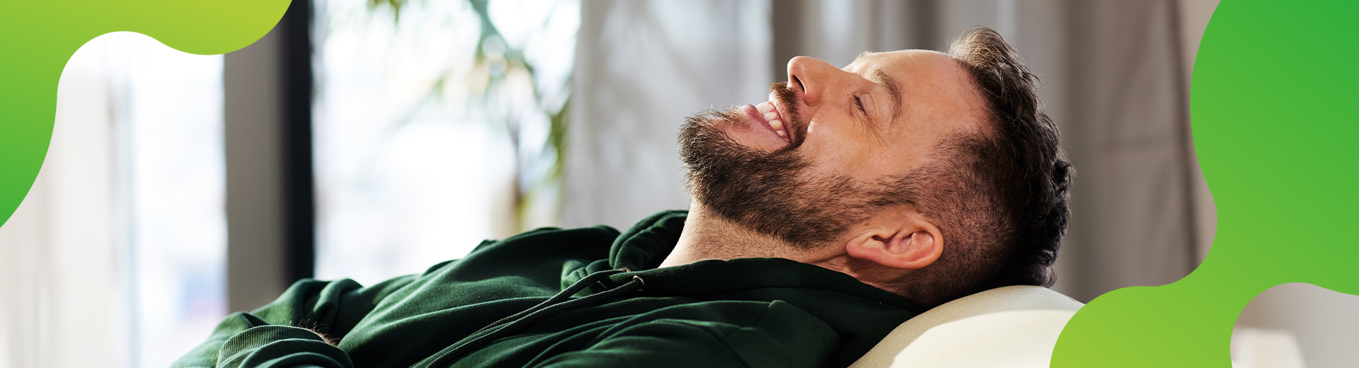 Eine Person lehnt sich auf einem Sofa entspannt zurück und lächelt zufrieden. 