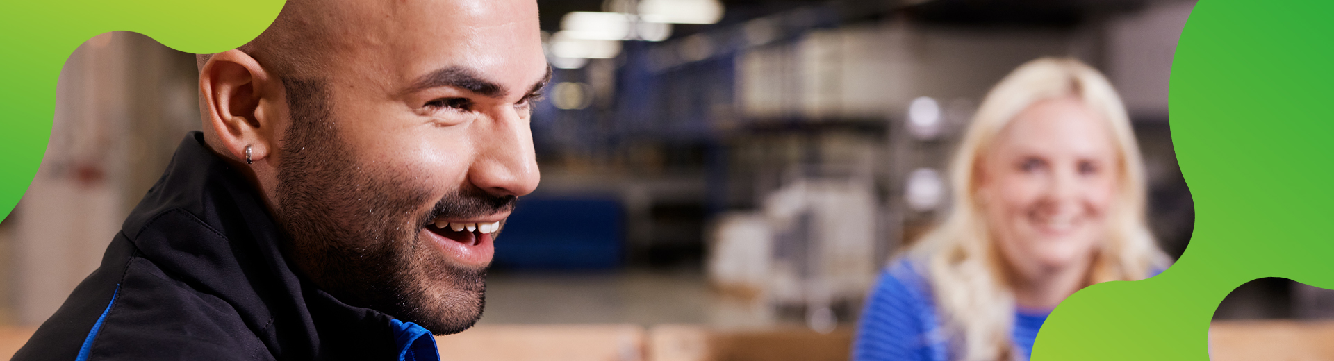 Ein Mann wird von der Seite gezeigt. Er lacht. Im Hintergrund ist eine lachende Frau zu erkennen.