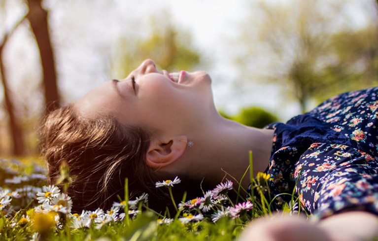 Frau liegt in Gänseblümchenwiese
