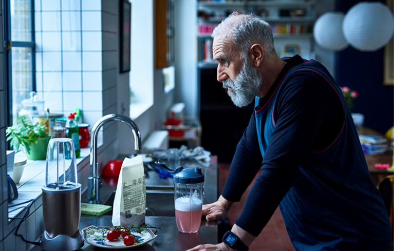 Ein Mann steht gedankenverloren in der Küche und macht sich Sorgen, wie er seine Aufgabe als Pflegeperson gut meistern kann.