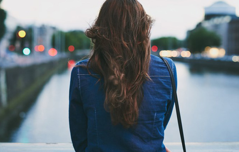 Nachdenkliche Frau von hinten schaut auf Fluss